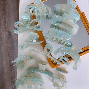Detail of mint green marble acetate hair claws with ginkgo leaf and butterfly designs