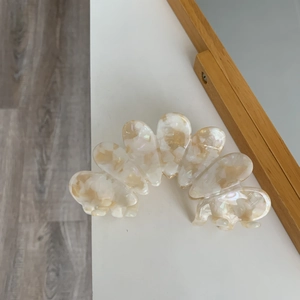 Detail of large acetate hair claw clip with creamy pearl finish and marble texture