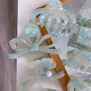 Detailed set of mint green marble cellulose hair claws with pearl and bow designs