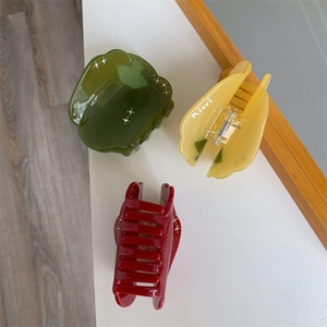 Détail de pinces à cheveux en acétate en forme de poivron, couleurs vert, jaune et rouge
