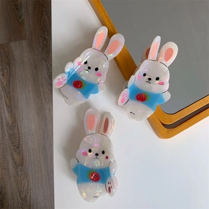 Close-up of three iridescent cartoon bunny hair claws featuring pink ears and strawberry detail