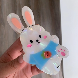 Detailed close-up of a cute pearlized white rabbit hair claw clip with carrot pattern