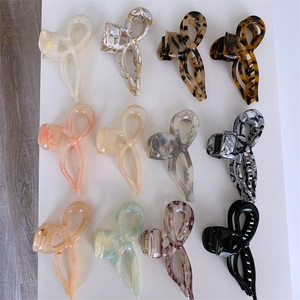 Macro view of 12 bow-shaped acetate hair claws in various marble and tortoiseshell patterns