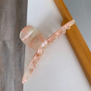 Macro detail of large acetate hair claw clip with pink and cream marble texture