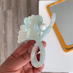 Detail of ginkgo leaf hair claw clip in teal acetate with pearl accent and glossy finish
