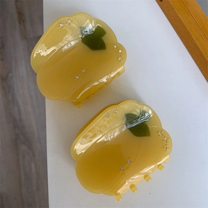 Détail des pinces à cheveux en acétate en forme de poivron jaune avec strass et tige verte