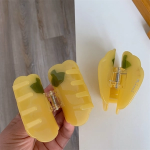 Détail de la pince à cheveux en forme de poivron jaune avec accents de feuilles vertes