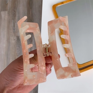 Detailed close-up of a large pink marble acetate hair claw clip with geometric design