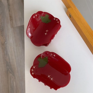 Détail de pinces à cheveux piment rouge avec feuilles vertes et strass brillants