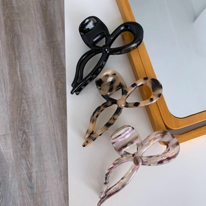 Three large acetate bow hair claws in black, tortoiseshell, and marble purple textures