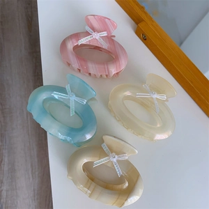 Détail de quatre pinces à cheveux macaron avec texture marbrée et nœuds en dentelle blanche