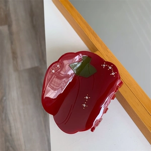 Détail de la pince à cheveux poivron rouge avec finition brillante et petits strass