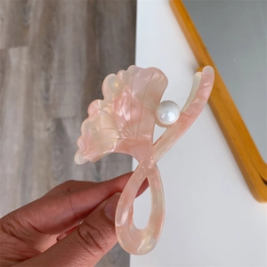 Detail view of pink ginkgo leaf hair claw clip made of acetate with a white pearl accent