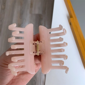 Detail showing pink acetate hair claw clip with golden metal spring for daily styling
