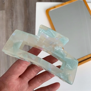 Close-up of a large rectangular acetate hair claw with blue and green marble patterns