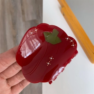 Détail d'une pince à cheveux piment rouge en acétate avec strass et perles dorées