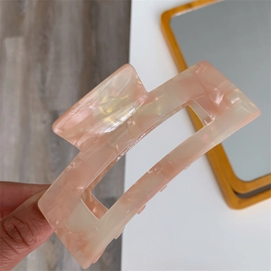 Close-up of a large pink acetate hair claw clip with marble texture for thick hair