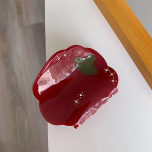 Gros plan d'une pince à cheveux en forme de poivron rouge avec des strass brillants