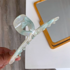 Detail of the marbled green and white acetate ginkgo leaf hair claw clip held in hand