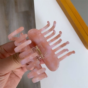 Detailed view of pink marble texture hair claw clip with golden metal spring for hair styling