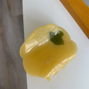 Détail de la pince à cheveux poivron jaune avec accents verts et strass étincelants