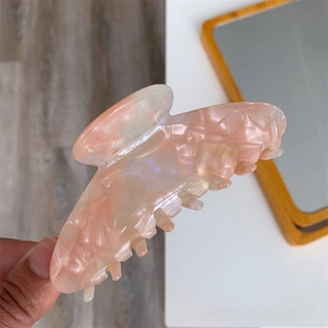 Close-up of pink marble acetate hair claw clip with pearl luster and metal spring