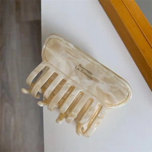 Detailed macro view of cream marbled acetate hair claw clip with Barrette La France gold logo