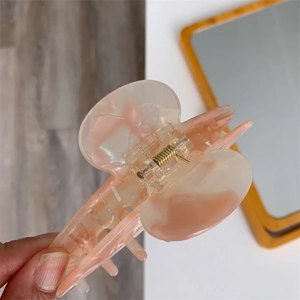 Detail of large peach pink acetate hair claw clip with marble texture and gold spring