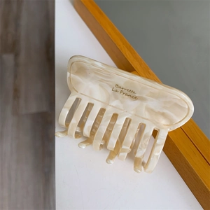 Detailed macro view of cream acetate hair claw clip with golden Barrette La France text