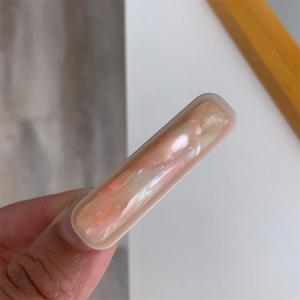 Macro detail of rectangle acetate hair claw featuring pink marble texture and cream trim