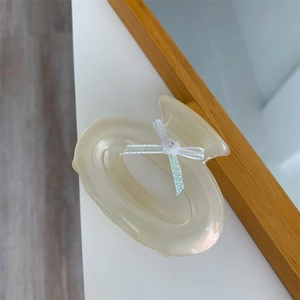 Détail d'une pince à cheveux crème nacrée avec petite fleur blanche et ruban iridescent
