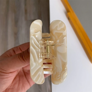 Close-up of cream white marbled acetate hair claw clip with a strong gold metal spring