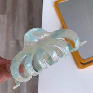 Close-up of mint green cellulose acetate hair claw clip with marble texture