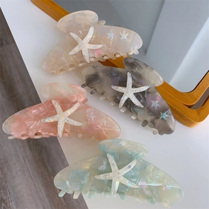 Detailed view of four acetate starfish hair claws in pink, white, grey, and green marble