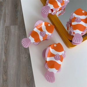 Dettaglio di tre mollette per capelli a forma di pesce pagliaccio in acetato arancione