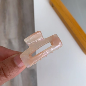 Detail of pink acetate hair claw clip showing marble texture and glossy finish