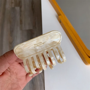 Close-up of marble acetate hair claw with gold Barrette La France text detail