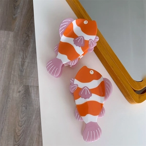 Dettaglio di graziose mollette per capelli a forma di pesce rosso arancione in acetato