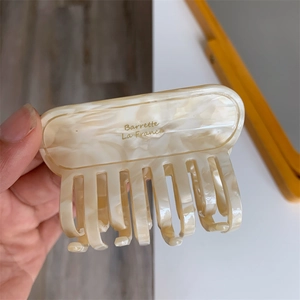 Close-up of cream marble texture acetate hair claw clip with golden Barrette La France text