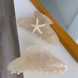 Detailed view of cream iridescent starfish hair claws with sparkling sequins and resin finish