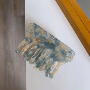 Detail view of large blue and white marble acetate hair claw clip with gold lettering