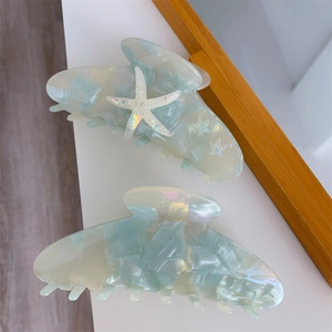 Detail of starfish hair claw clip with mint green pearlescent acetate texture and glitter