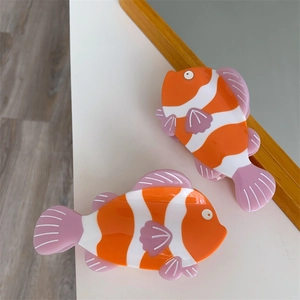 Dettaglio di fermagli per capelli a forma di pesce in acetato arancione lucido con strisce
