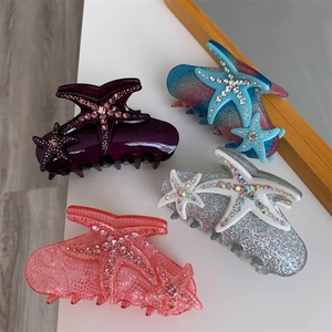 Detailed view of rhinestone-studded starfish hair claws in gradient and glitter finishes