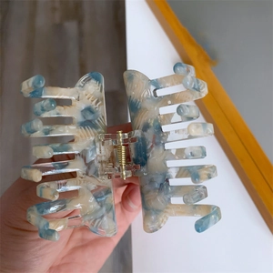 Detail of blue marble acetate hair claw clip with golden spring and strong grip