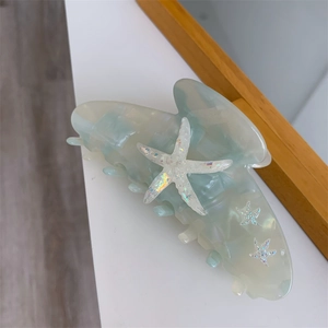 Macro detail of starfish claw clip with pearlescent acetate and glitter accents