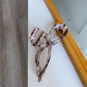 Detailed close-up of large acetate bow hair claw with purple marble texture design