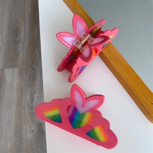 Detail view of pink heart hair claw clips with rainbow stripes and metal spring