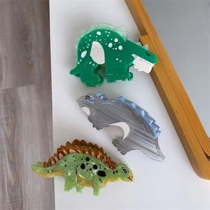 Detailed view of acetate dinosaur hair claws in green, grey, and spotted patterns