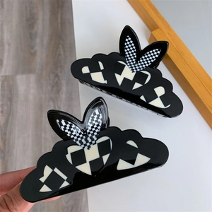 Close-up of cloud-shaped black acetate hair claw with checkerboard heart detail